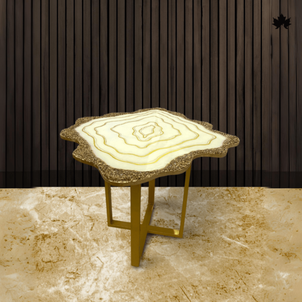 Artistic Luxury Agate accent table featuring an organic, free-form top designed with concentric layers of white and yellow resin, mimicking the intricate patterns of a natural geode. The table is accented with a textured, golden-crusted edge and is supported by sleek, golden metal legs. Set against a dark wood-paneled background and a creamy marble floor, this table combines elegance with a touch of earthy appeal.