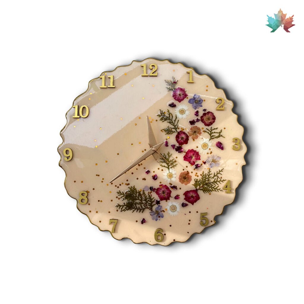 Blossom Serenity Luxury Timepieces For Home table clock by Fankaarlok featuring a gentle cream background adorned with a diagonal splash of golden hues and scattered real flowers, crafted in resin. The clock face is uniquely designed with golden numerals in a soft, flowing font, providing both functionality and a decorative floral charm.