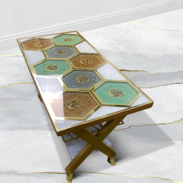 Elegant console table featuring a geometric honeycomb design with hexagonal tiles in shades of turquoise, gold, and brown, each bordered in gold. The table stands on a golden X-frame with caster wheels, showcasing a luxurious and modern aesthetic. This piece is positioned on a glossy marble floor, reflecting its polished surface and intricate details.