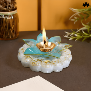 Decorative diya holder from Fankaarlok, featuring a floral design with a translucent white and vibrant blue resin petals, accented with gold leaf details. A lit diya sits in the center, casting a warm glow, ideal for festive decor and celebrations.