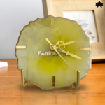 Verdant Vignette - Classic Table Clock by Fankaarlok, featuring a translucent green resin design with sleek gold accents and clock hands, placed elegantly on a wooden surface next to home decor items.