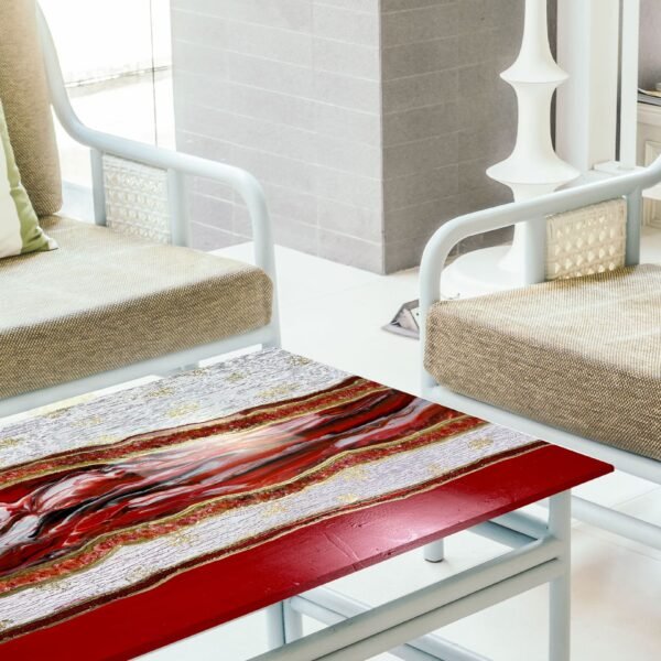 Modern artistic coffee table featuring a distressed silver and red resin top, creating a striking abstract pattern. The table is framed with a bold red border and supported by black metal legs. A small glass jar with a festive arrangement of greenery and white berries adds a touch of holiday spirit, complementing the vibrant and textured surface of the table.