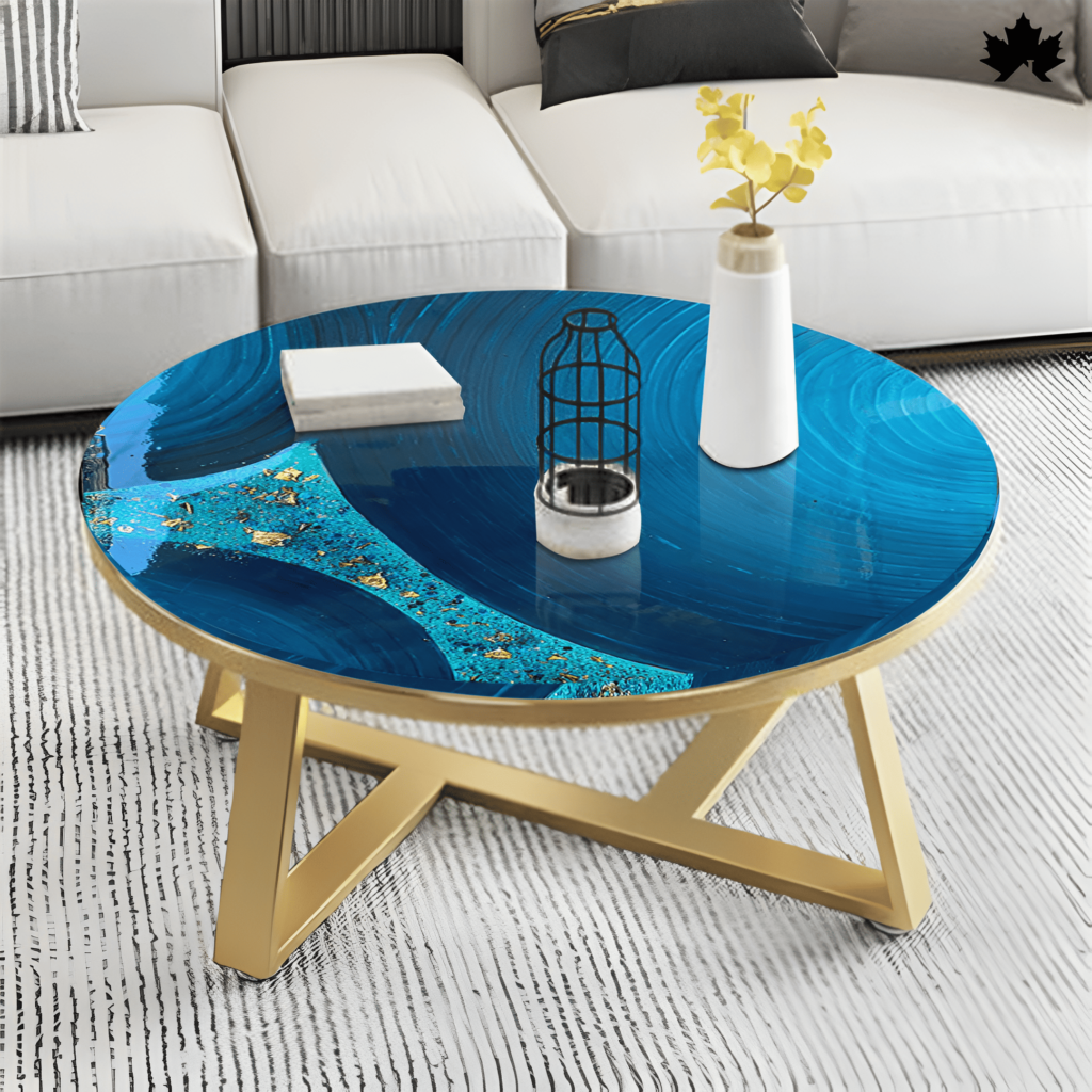 Stunning round center table from Fankaarlok, featuring a deep blue resin top with swirling patterns and gold and turquoise accents, creating an oceanic vibe. The table is supported by a golden metal frame in a simple yet elegant X-shape, placed in a modern living room setting with a white sectional sofa and minimalist decor, adding a vibrant pop of color and artistic flair to the space.