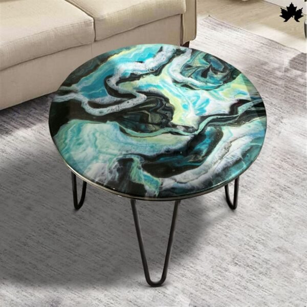 Exclusive Artistic round coffee table featuring a swirling marble pattern in shades of blue and green with a sleek black metal base, enhancing the modern aesthetic of a bright living room.