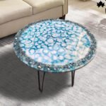 Elegant Artistic resin coffee table featuring a captivating bubble pattern in serene blue tones with sparkling accents, supported by slender, black metal legs, adding a modern touch to the living space.