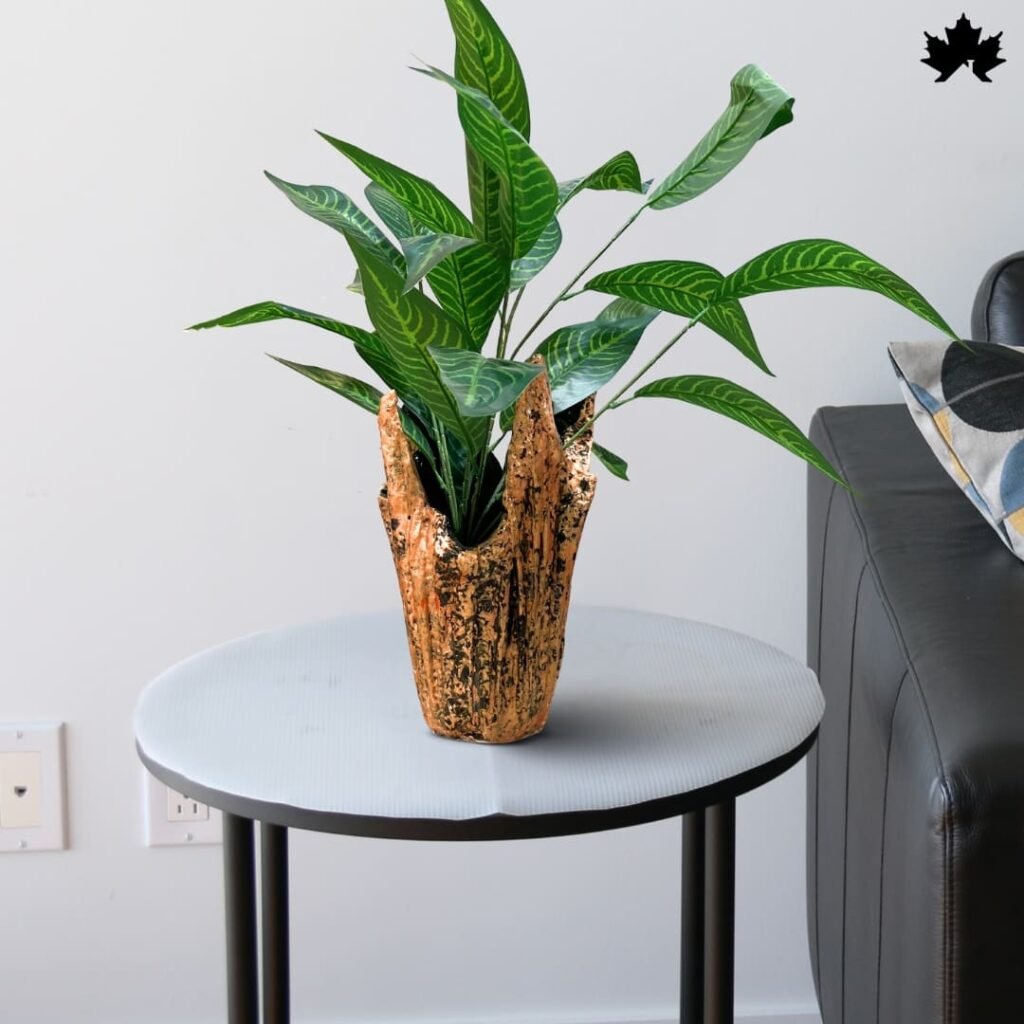 A Unique Plant Holders featuring a textured gold and dark blue finish, positioned on a gray round table. This stylish and contemporary vase enhances the vibrant green leaves of the Dieffenbachia plant it hosts, ideal for adding a touch of luxury to any modern living space.